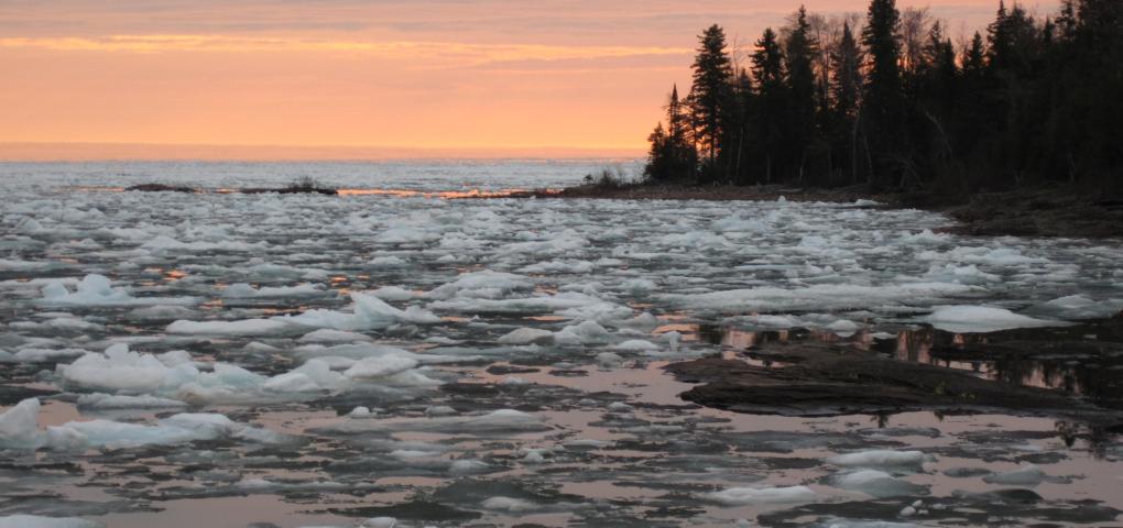 yellow and orange sunrise showing floating ice patterns on Lake Superior
