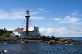 white lighthouse on rugged shore with very blue sky behind