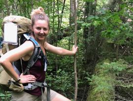 Tiff DeGroot stands in a forest wearing a large backpacking bag.