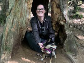 Margaret Armstrong, KLT Adminstrative and Development Coordinator, poses with her dog at the base of a tree.
